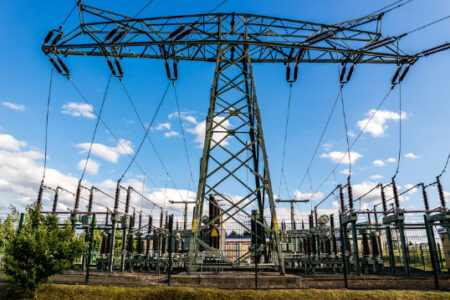 An electric substation set against a blue sky with white clouds